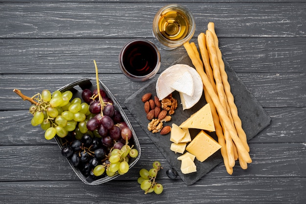 Free photo tray with cheese and grapes beside glass with wine