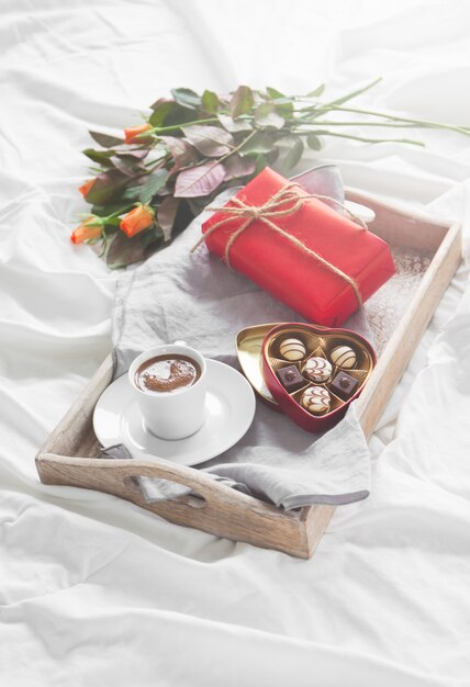 Tray with a cup of coffee flowers and chocolates