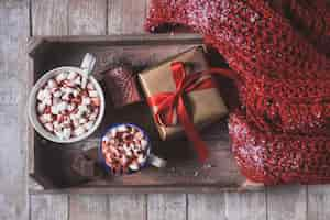 Free photo tray with cups with marshmallows and a gift