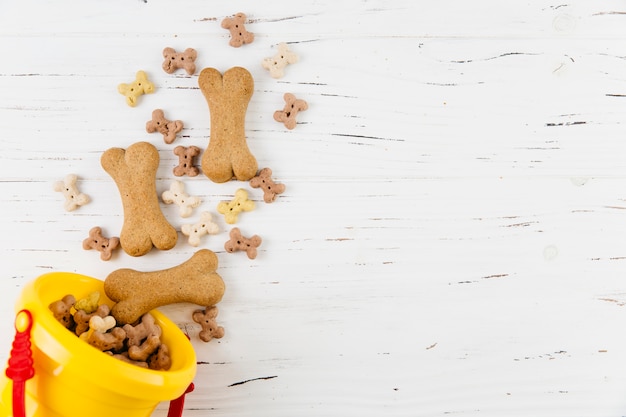 Treats for dogs in bucket on white wooden surface