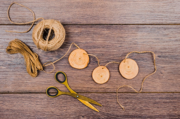 Tree stump slices with jute thread and scissor on wooden desk