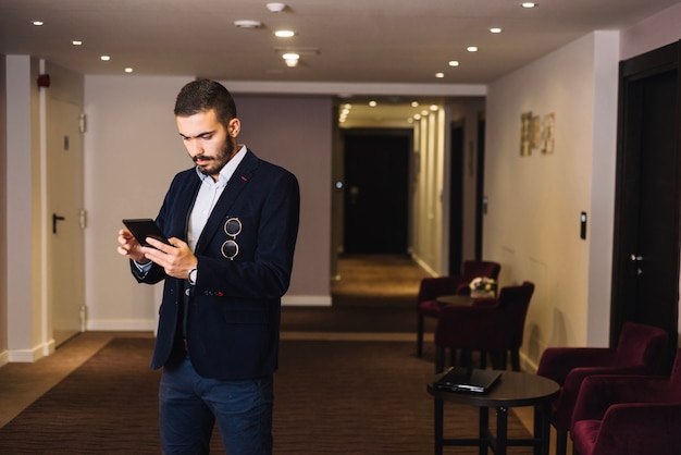 Free photo trendy businessman in hall with gadget