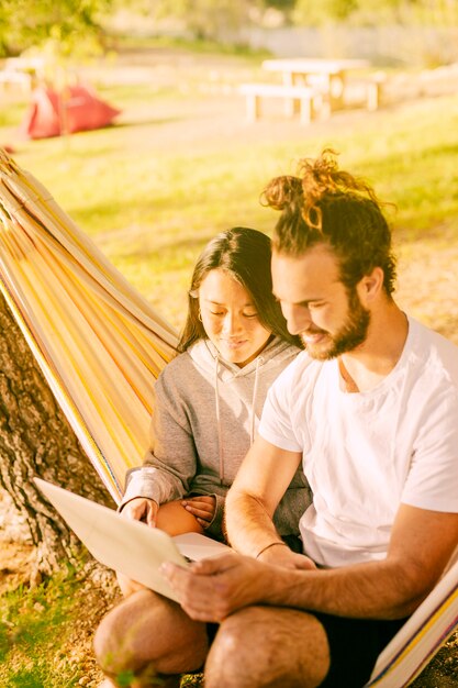 Trendy couple relaxing together in hammock outdoors