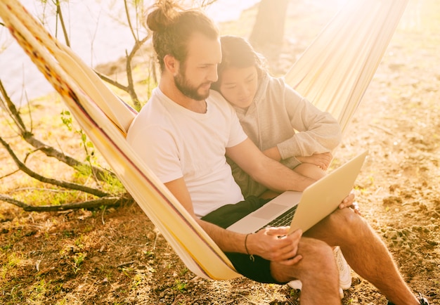 Trendy couple resting together in hammock outdoors