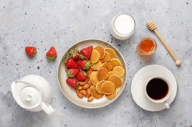 Trendy food - mini pancake cereal. Heap of cereal pancakes with berries and nuts.