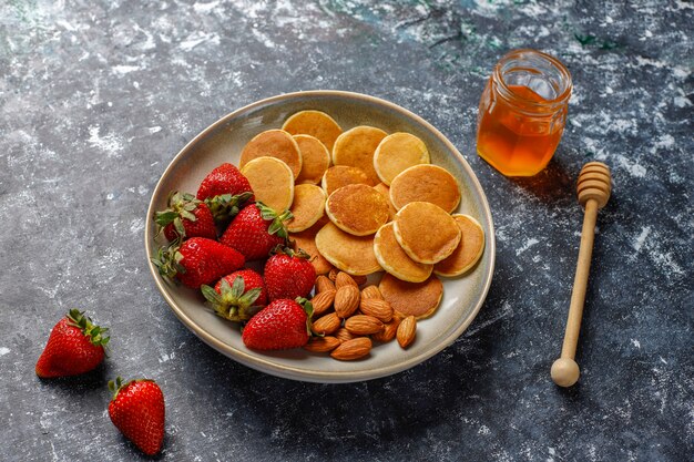 Trendy food - mini pancake cereal. Heap of cereal pancakes with berries and nuts.