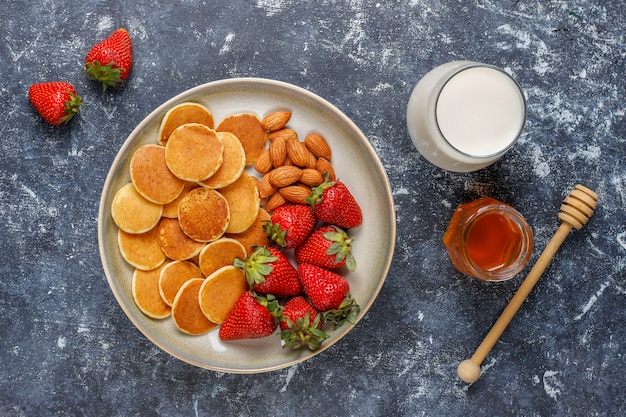 Trendy food - mini pancake cereal. Heap of cereal pancakes with berries and nuts.