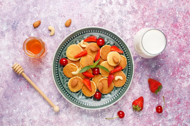 Trendy food - mini pancake cereal. Heap of cereal pancakes with berries and nuts.