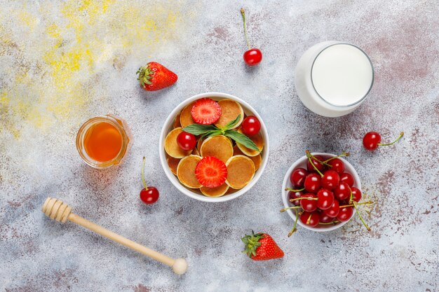 Trendy food - mini pancake cereal. Heap of cereal pancakes with berries 