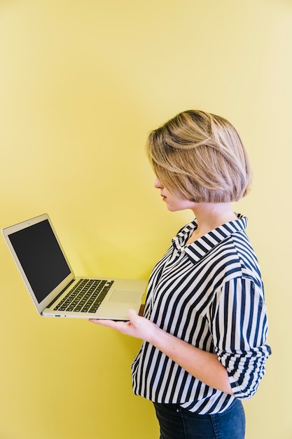 Free photo trendy girl watching laptop on yellow