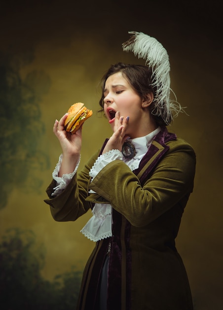 Foto gratuita look trendy donna ritratto del periodo rinascimentale mangiare hamburger