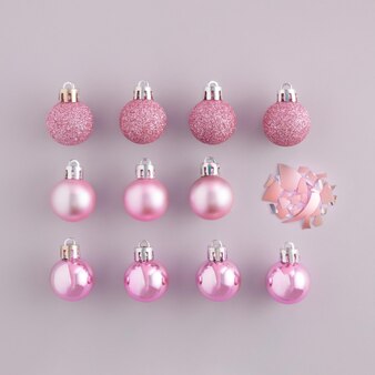 Trendy pattern made of pink christmas baubles and single broken christmas ornament happy new year