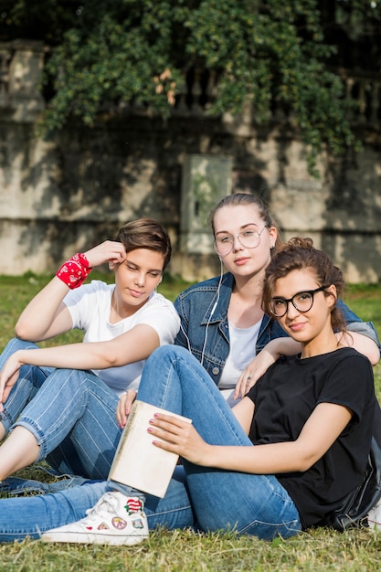 Trendy relaxed friends sitting in park