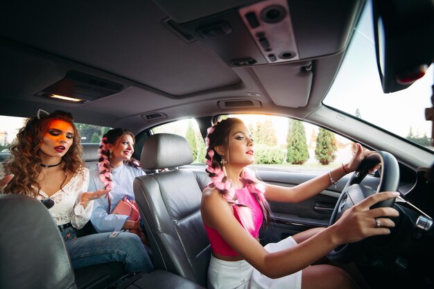 Trendy stylish trendy girlfriends go in the car listening to music and having fun together They go shopping for their city Friends rest together and shopping is always together