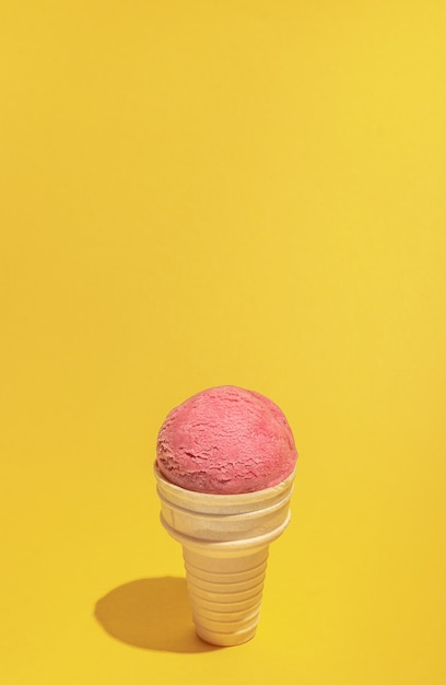 Trendy sunlight summer background made with raspberries pink ice cream with waffle cone. minimal summer background. food styling concept.