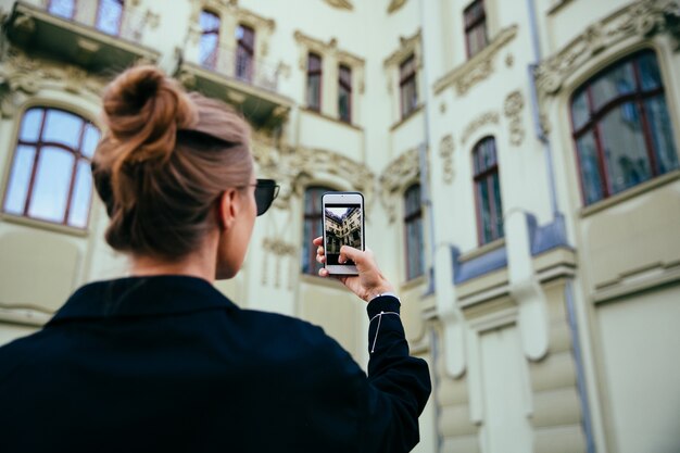Модная женщина с фотографией старого здания, архитектуры, с помощью мобильного телефона