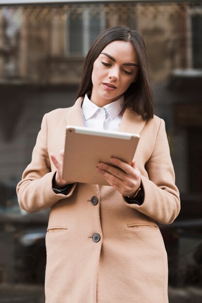 Trendy woman using tablet on street