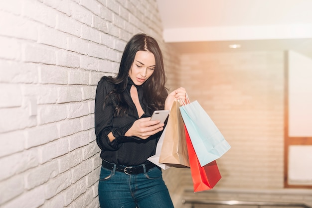 Foto gratuita donna alla moda con borse utilizzando il telefono