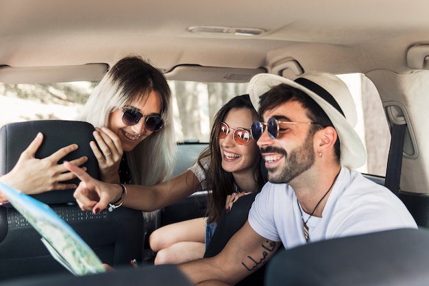 Модные молодые друзья, сидящие внутри современного автомобиля, глядя на карту