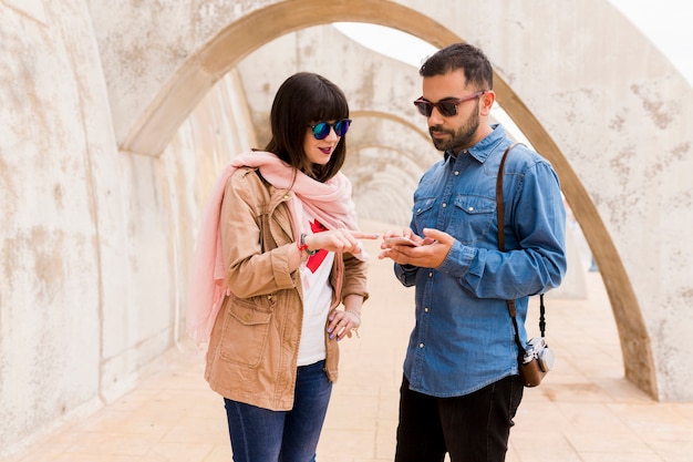 Trendy young woman pointing finger toward mobile phone