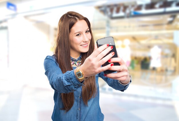 スマートフォンで自分撮りを取るトレンディ若い女性