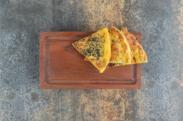 Triangle pastry with poppy seeds on a wooden board