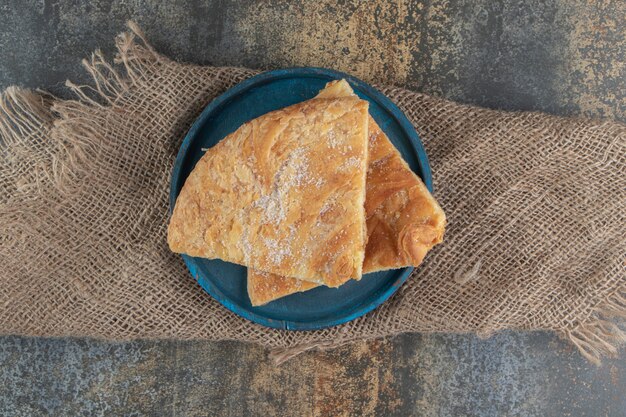 Triangle pastry with sugar on a blue plate