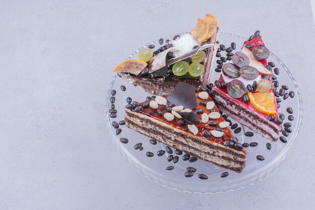 Triangle shaped chocolate cake slices with nuts and fruits in a glass platter with beans