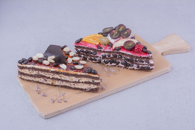 Triangle shaped chocolate cake slices with nuts and fruits on a wooden platter