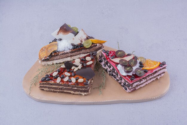 나무 접시에 견과류와 과일 삼각형 모양의 초콜릿 케이크 조각