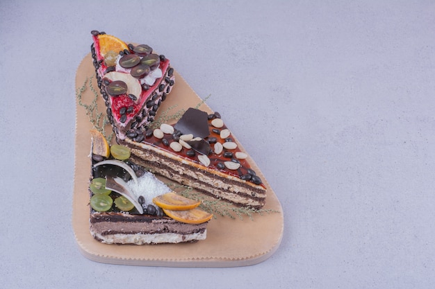 Triangle shaped chocolate cake slices with nuts and fruits on a wooden platter