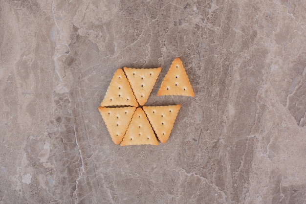Triangle shaped crackers on marble surface.