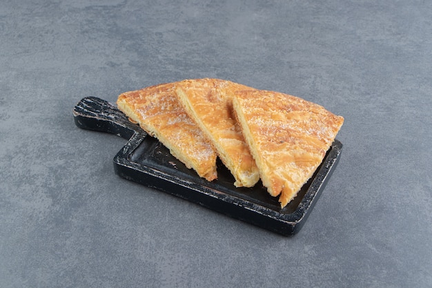 Triangle shaped pastries on black cutting board. 
