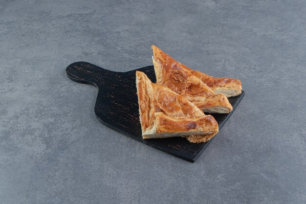 나무 판자에 치즈를 채운 삼각형 모양의 패스트리.