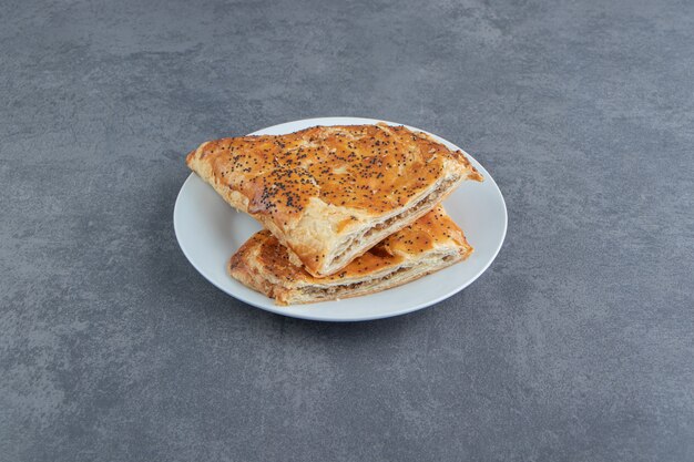 Triangle shaped pastries filled with meat on white plate.