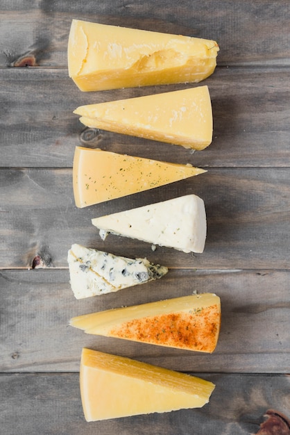 Triangular cheese chunk arranged in row on wooden plank