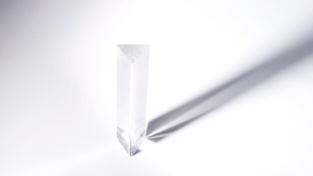 Triangular prism crystal with dark shadow on white background