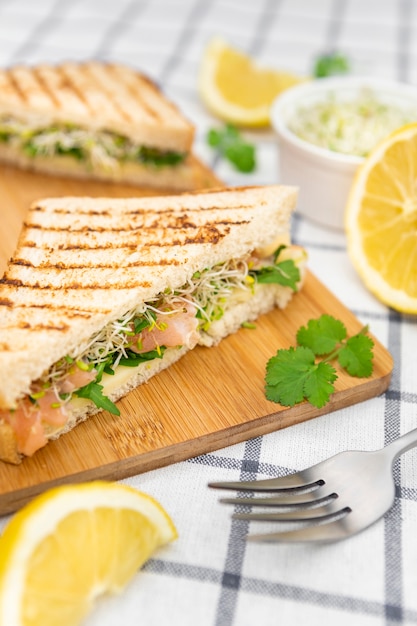 Free photo triangular sandwiches on chopping board with fork and parsley