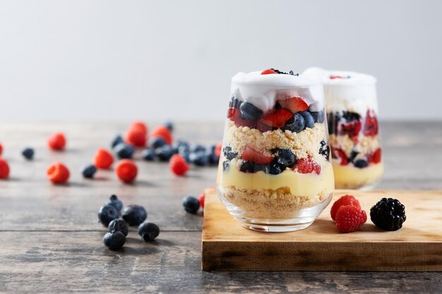 Trifle dessert with berries and cream on wooden table