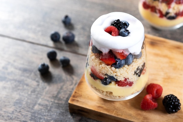 Trifle dessert with berries and cream on wooden table