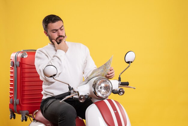 Foto gratuita concetto di viaggio con uomo impegnato seduto sulla moto con la valigia su di essa su giallo