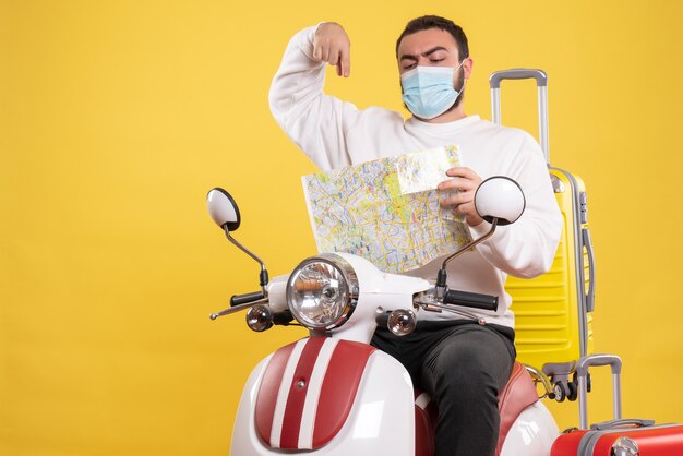 Концепция поездки с уверенным в себе парнем в медицинской маске, сидящим на мотоцикле с желтым чемоданом на нем