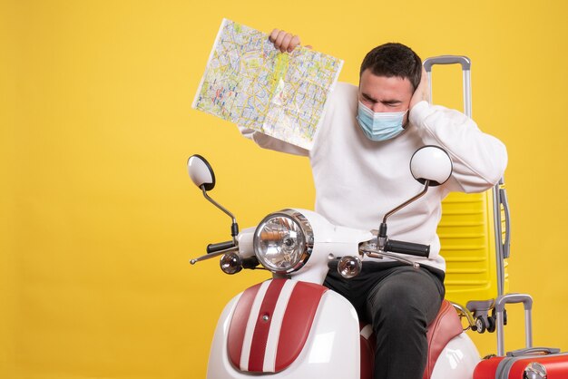 그것에 노란색 가방과 함께 오토바이에 앉아 노란색에지도를 보여주는 의료 마스크에 문제가있는 사람과 여행 개념