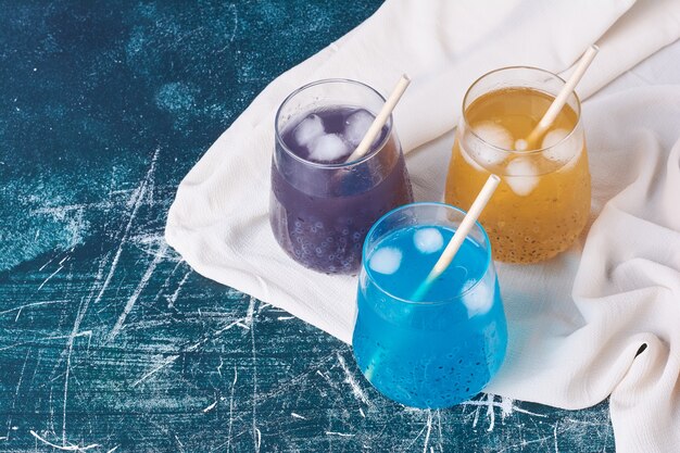 Triple color cups of drink on blue.