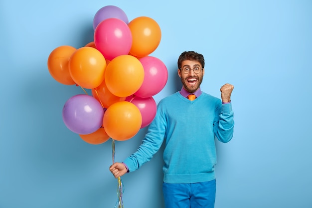 Triumphing joyous young gentleman raises clenched fist, celebrates getting new job