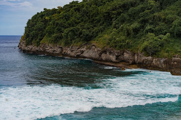 열대 배경, 푸른 물이 있는 해변, 파도가 돌에 부서진다