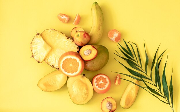 Tropical fruits and berries on a yellow background flat lay