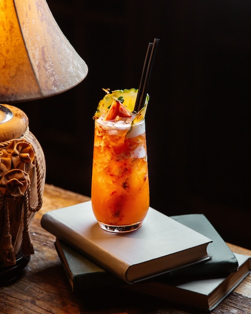 Tropical juice filled with fruits placed on books