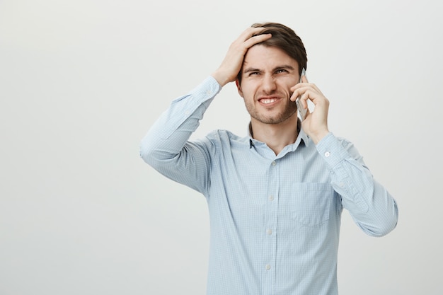 Troubled businessman talking phone, facepalm disappointed