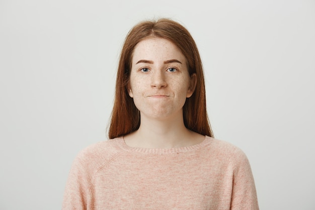 Troubled disappointed redhead woman biting lips upset